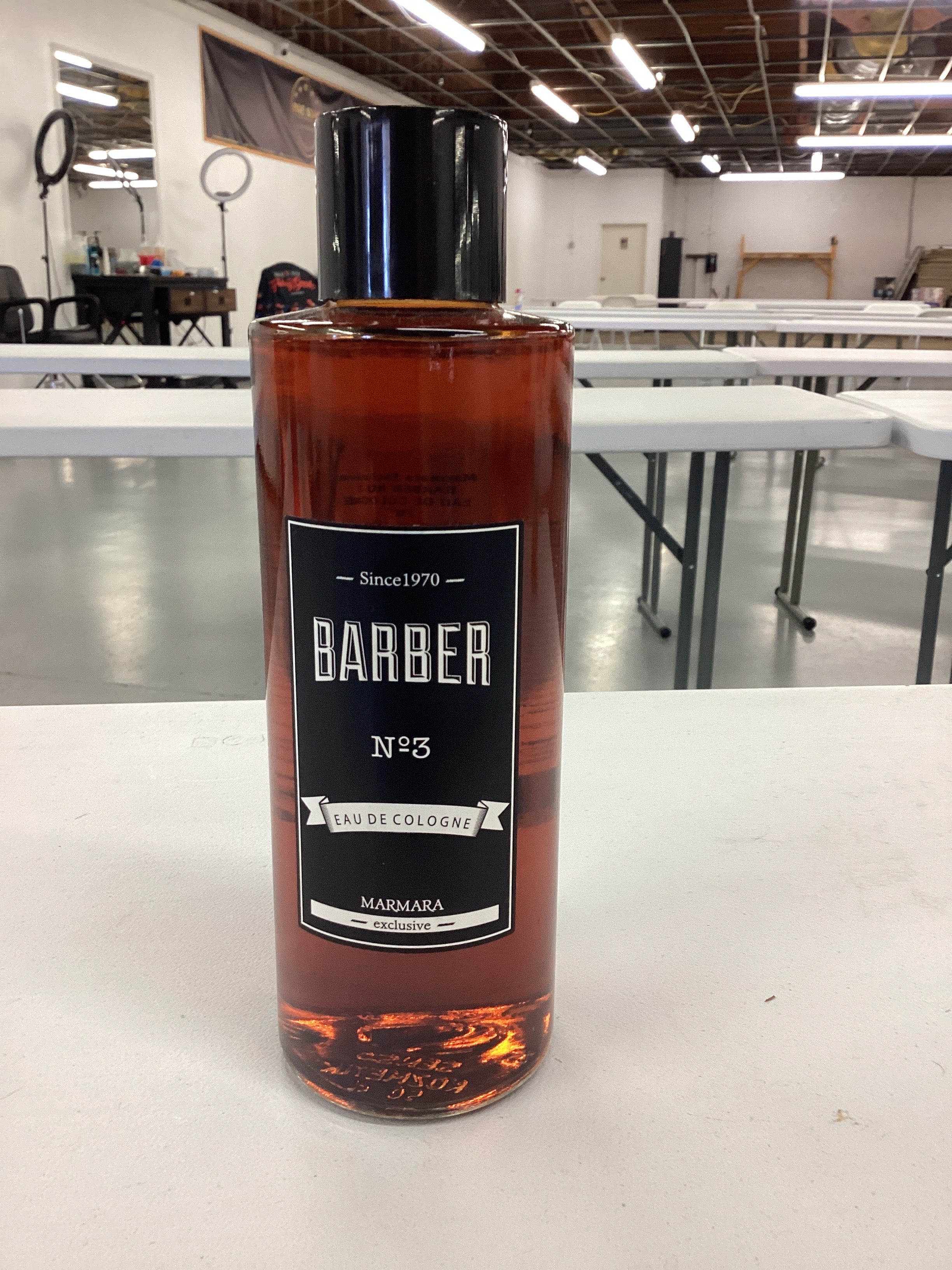 Bottle of Barber No. 35 on a white surface with a blurred barbershop background.