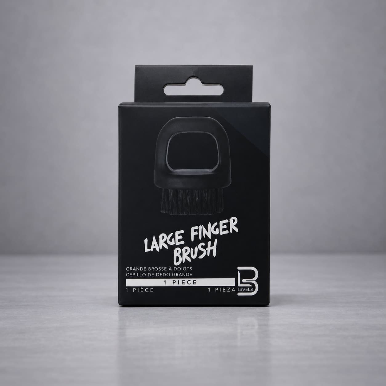 Black packaging of a large finger brush on a gray background