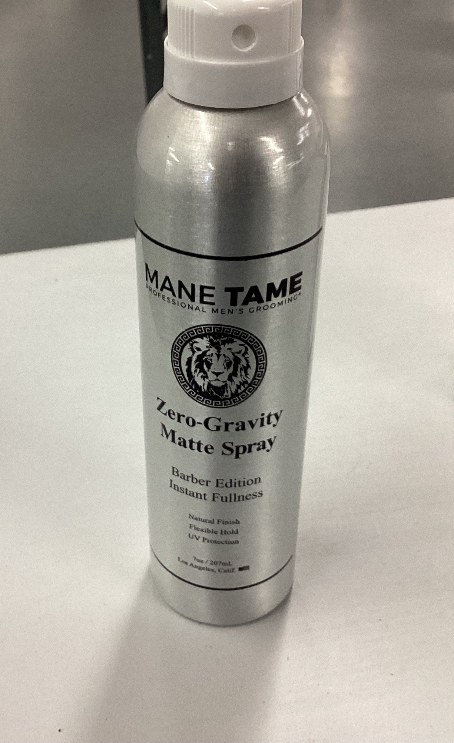 Mane Tame Zero-Gravity Matte Spray bottle on a table with a box in the background