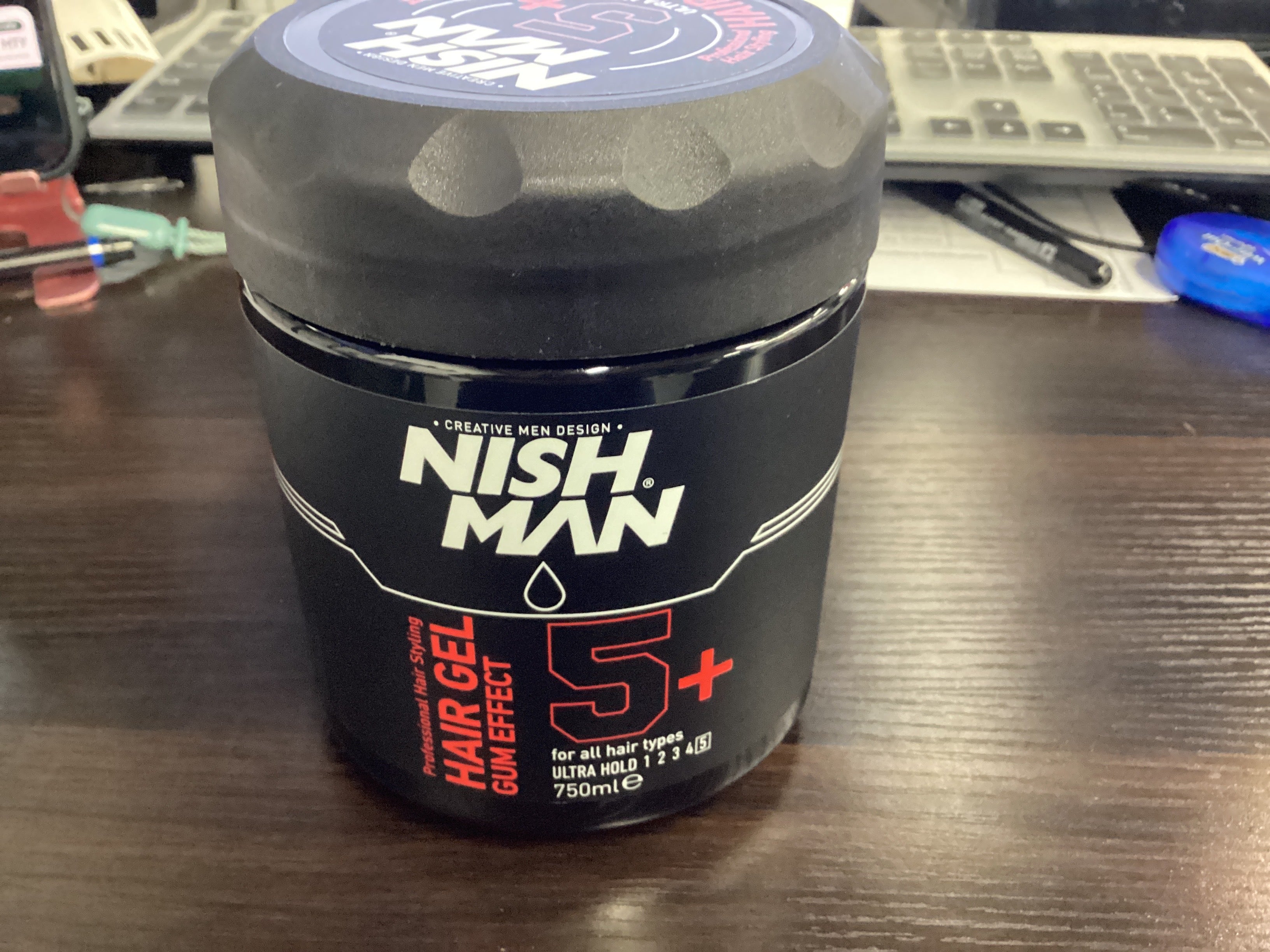 Nish Man hair gel jar on a desk with office items in the background