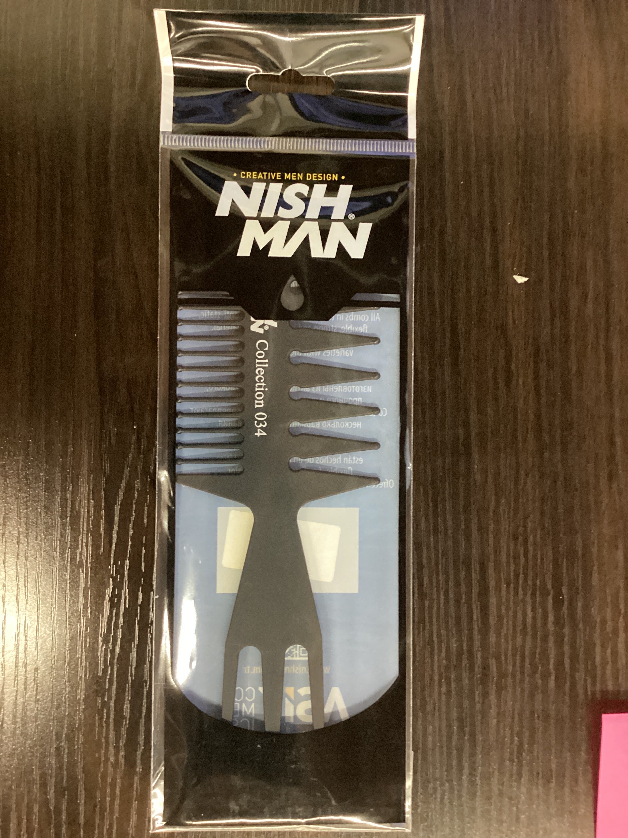 Packaged comb with 'Nish Man' branding on a wooden surface